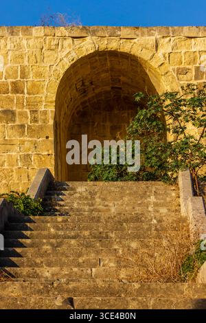 Ancient Stone Archway with Stairs Framed by Sunlight and Greenery Stock Photo