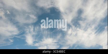 Wispy White Clouds in Bright Blue Sky Stock Photo