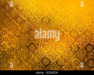 Intricate golden ornamental pattern with embossed floral and geometric motifs on a textured surface. malaysia Stock Photo