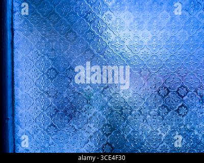 Close-up of a decorative frosted glass window with intricate floral patterns and a blue tint.  malaysia Stock Photo