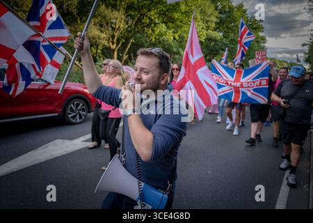Epping Forest District of Essex, UK. 14th August 2025. Pictured: Callum Barker of Homeland Party leads a march through Epping with anti-migrant protesters after demonstrations outside The Bell Hotel currently being used to house asylum seekers. Credit: Guy Corbishley/Alamy Live News Stock Photo