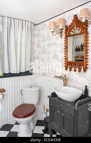 Cozy and stylish bathroom featuring vintage furniture, a distinct antique mirror, and warm lighting. European country-inspired interior design. A blen Stock Photo