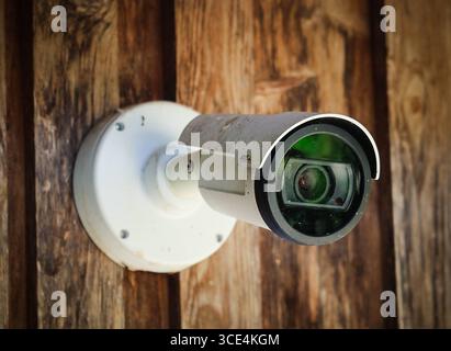 14.08.2025, Handenberg, AUT, Unterwegs in Oberösterreich, Themenbild, Symbolbild, Verschiedene Themenbilder, Videoüberwachung, Kamera, Überwachung, im Bild Das Bild zeigt eine Überwachungskamera, die an einer Holzoberfläche montiert ist. Die Kamera hat ein weißes Gehäuse mit einem runden Objektiv und ist durch Schrauben befestigt. Unter der Kamera hängt ein quadratisches Schild mit einem blauen Hintergrund und einem stilisierten Bild einer Kamera in Weiß. Darunter steht in klarer Schrift Videoüberwachung .Die Holzoberfläche wirkt rustikal und trägt zur Atmosphäre des Ortes bei. Die Kamera und Stock Photo