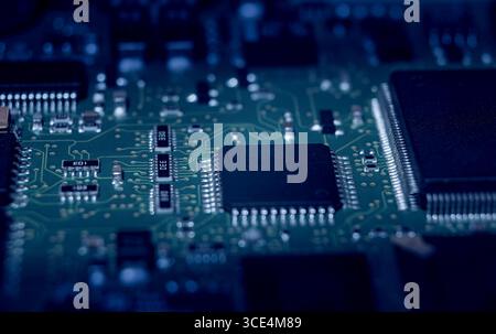 Detailed examination of microchips and circuitry on an electronic board illustrates the complexity of modern technology and design at night. Stock Photo