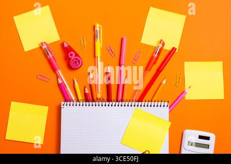 Spiral notebook, sticky notes, and colorful school supplies on orange background. Perfect for education, study, and planning themes. Stock Photo