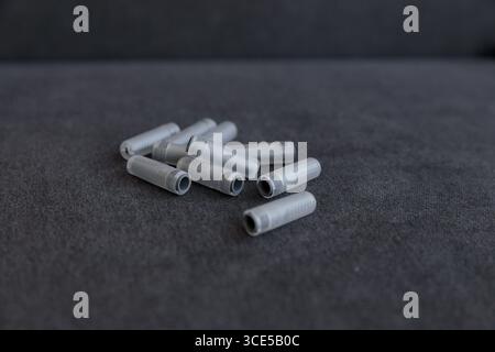 This image captures a cluster of gray plastic tubes neatly arranged on a dark, textured surface, highlighting their utilitarian design and functional Stock Photo