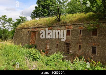 Overgrown stone wall of Owcza Góra Fortress with small barred windows and grassy rooftop in Kłodzko, Poland Stock Photo