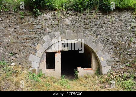 Stone entrance to an underground tunnel at Fort Owcza Góra in Kłodzko, Poland, partially ruined and overgrown Stock Photo