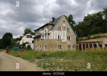 Rural residential house from 1993 with overgrown yard and cloudy summer sky in Kłodzko, Poland Stock Photo