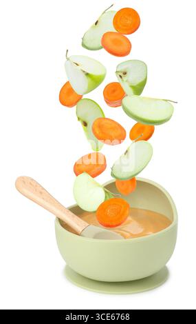 Baby food. Apple and carrot slices falling into bowl of puree on white background Stock Photo