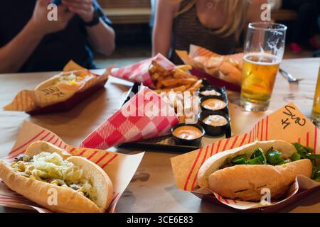 Fresh grilled sausages in buns on table inside Wurstküche Restaurant a Bavarian styled beer hall, Los Angeles, Los Angeles County, California, USA Stock Photo
