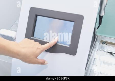Asian adult female using medical touchscreen device in modern clinical setting for health monitoring. Stock Photo