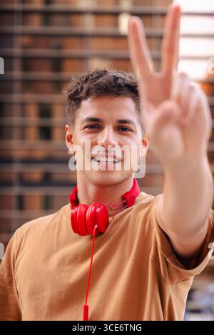 Happy young man raising fist in celebration wearing red headphones outdoors Stock Photo