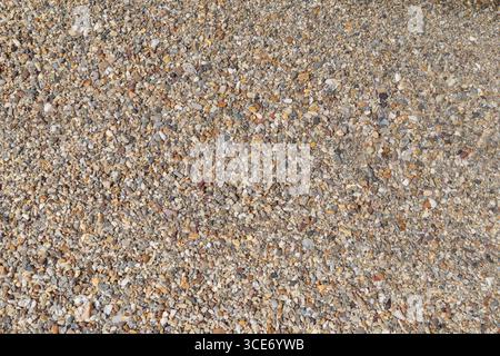 Small pebbles on the shore in a beach on sunny day, viewed from above. Abstract natural travel, vacation and summer background. Stock Photo