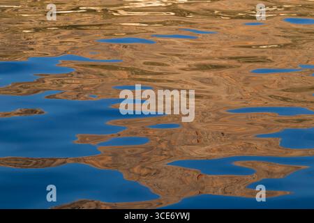 Abstract blue and brown reflections on rippled water surface. Background with abstract natural shapes and vibrant colors. Stock Photo