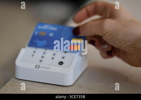 Cremona, Italy July 19th 2025 Woman using blue credit card for contactless payment on white SumUp POS terminal, ensuring secure and convenient transac Stock Photo