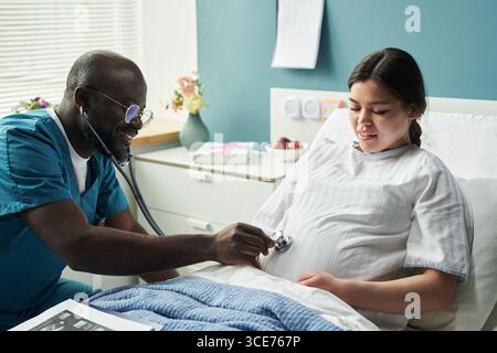 Middle Aged Black Male Doctor Examining Pregnant Young Caucasian Woman Stock Photo