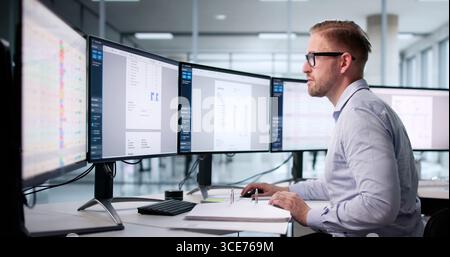 Young Male Accountant Using Electronic Software To Automate Invoice Calculations. Stock Photo