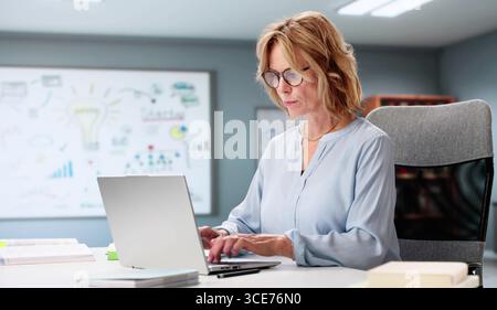 Confident Elderly Female Math Professor Helping Student With Laptop Tutoring Stock Photo