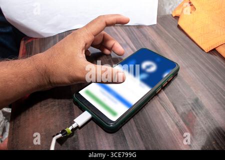 The mobile being used by the hand, The mobile is placed on the table Stock Photo