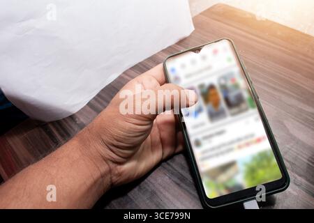 The mobile being used by the hand, The mobile is placed on the table Stock Photo