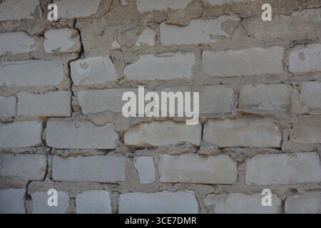 Construction, building materials, garbage, background of building bricks. Wall of white smooth brick with gray cement masonry, incorrect masonry. Stock Photo