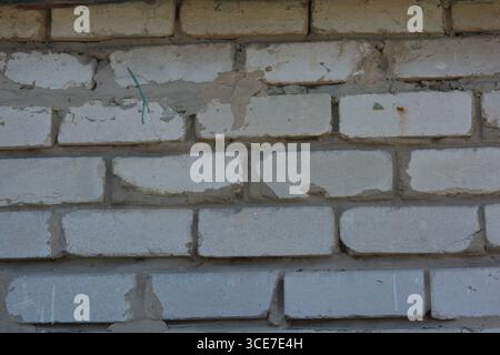 Construction, building materials, garbage, background of building bricks. Wall of white smooth brick with gray cement masonry, incorrect masonry. Stock Photo