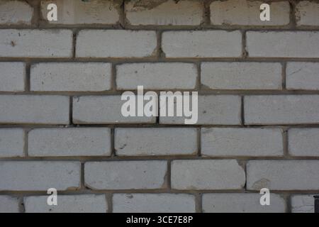 Construction, building materials, garbage, background of building bricks. Wall of white smooth brick with gray cement masonry, incorrect masonry. Stock Photo