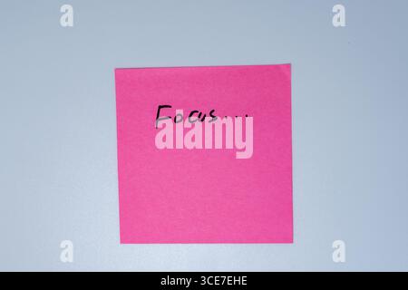 Pink Sticky Note with Handwritten Word Focus on White Background Stock Photo