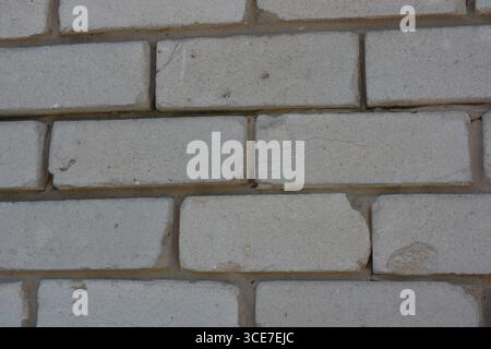Construction, building materials, garbage, background of building bricks. Wall of white smooth brick with gray cement masonry, incorrect masonry. Stock Photo