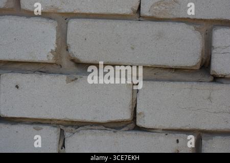 Construction, building materials, garbage, background of building bricks. Wall of white smooth brick with gray cement masonry, incorrect masonry. Stock Photo