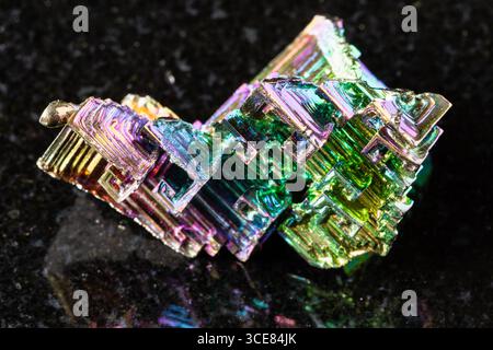 sample of raw grown bismuth crystals on black granite background close up Stock Photo