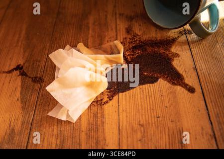 Overturned ceramic cup with spilled coffee on wooden table Dirty stain with napkins symbol of accident mess and cleaning problem Stock Photo