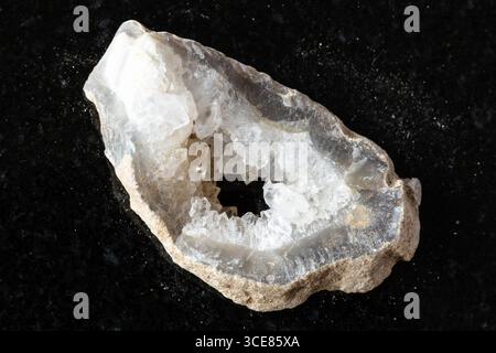 sample of cut layer of quartz-filled geode on black granite background close up Stock Photo