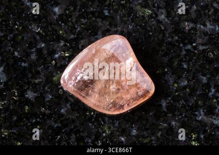 sample of polished pink tourmaline crystal on black granite background close up from Brazil Stock Photo