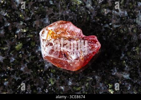 sample of rough hyacinth zircon mineral on black granite background close up from Tanzania Stock Photo