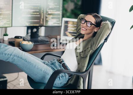 Young female programmer relaxing at her workspace in a casual home office setting Stock Photo