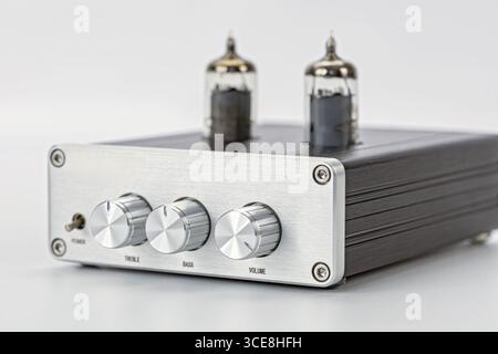 A silver audio amplifier with vacuum tubes metal front panel three control knobs modern design isolated on white background high fidelity retro style Stock Photo