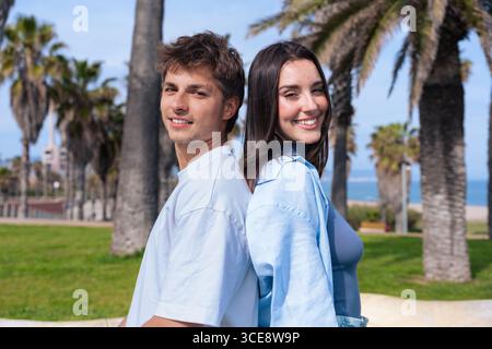 Smiling young couple standing back to back outdoors Stock Photo