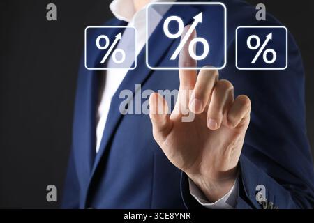 Businessman touching percent sign on virtual screen against black background, closeup Stock Photo