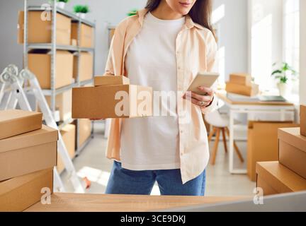 Internet store owner or inventory manager preparing parcels and using mobile phone Stock Photo