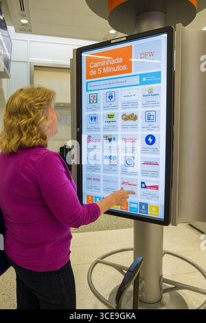 Woman using large interactive electronic display to find information on dining and services available inside Terminal E at the Dallas/Fort Worth Inter Stock Photo