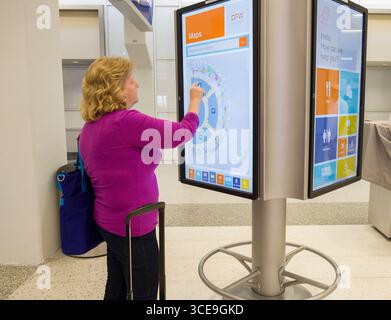 Woman using large interactive electronic display to find information on dining and services available inside Terminal E at the Dallas/Fort Worth Inter Stock Photo