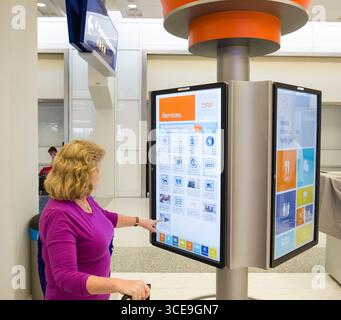 Woman using large interactive electronic display to find information on dining and services available inside Terminal E at the Dallas/Fort Worth Inter Stock Photo