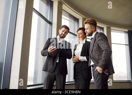 Group of three young confident business people discussing a work project during a meeting. Stock Photo