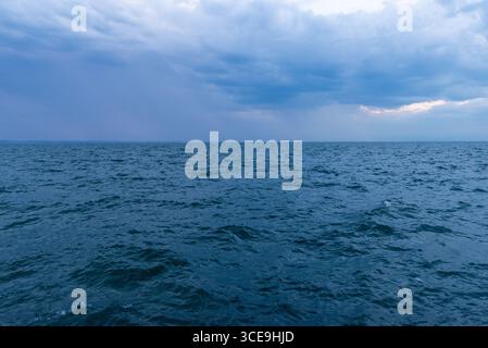 Blue ocean under cloudy sky with distant rain on the horizon, perfect for weather, travel, or adventure backgrounds Stock Photo