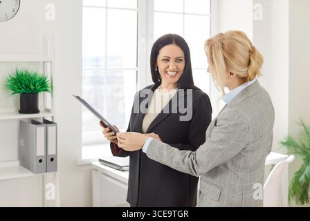 Two women colleagues working in office, discussing business project, collaborate together Stock Photo