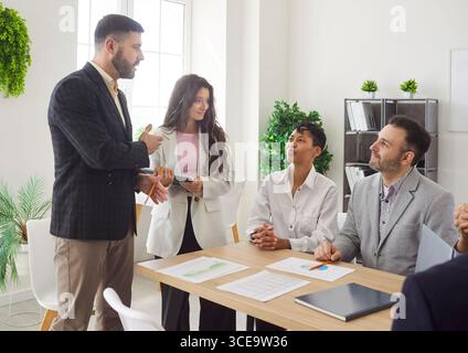 Diverse business people talking on a meeting sitting at the working place in office. Stock Photo