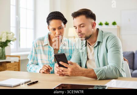 Female and male students gathering together, focused in smartphone, studying Stock Photo