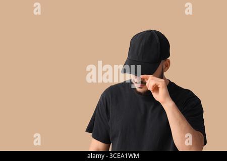 Handsome young man in stylish cap on beige background Stock Photo